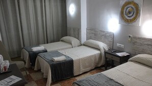 Ein Hotelzimmer mit zwei Betten, einem kleinen Tisch mit einer Kaffeetasse und einem Nachttisch mit einer Fernbedienung.