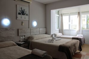 A hotel room with three beds, a large window, and a wall-mounted artwork. - Hostal Virgen del Rocio II (Torremolinos)