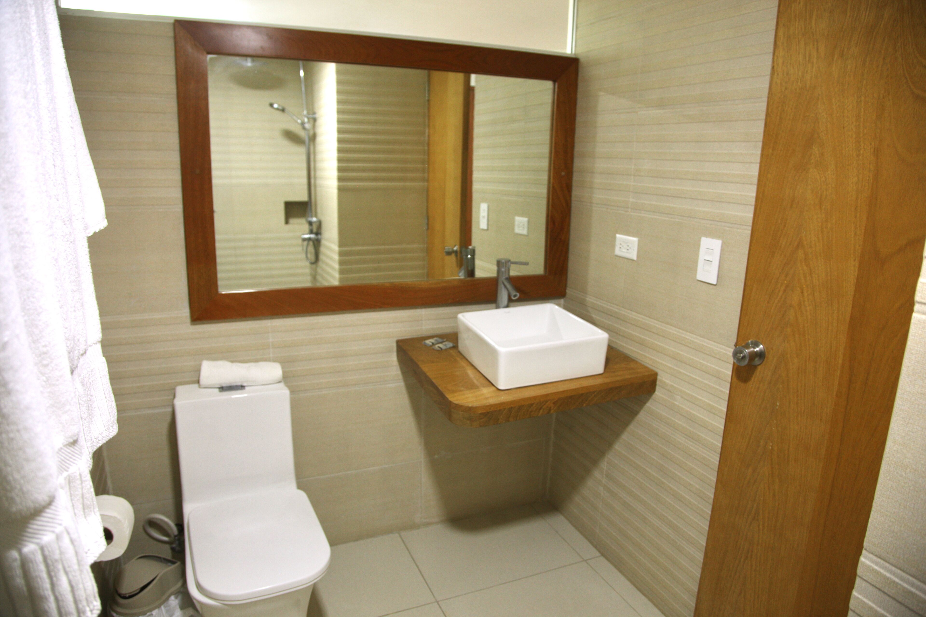 Un bany amb vàter, un lavabo, un mirall i una tovallola penjada a la paret.