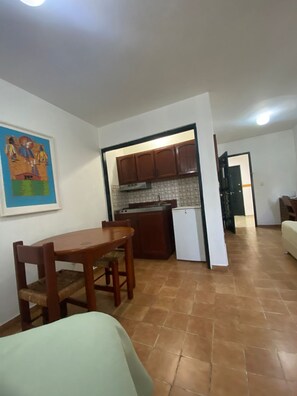 A compact living space with a dining area, kitchenette, and a door leading to another room.