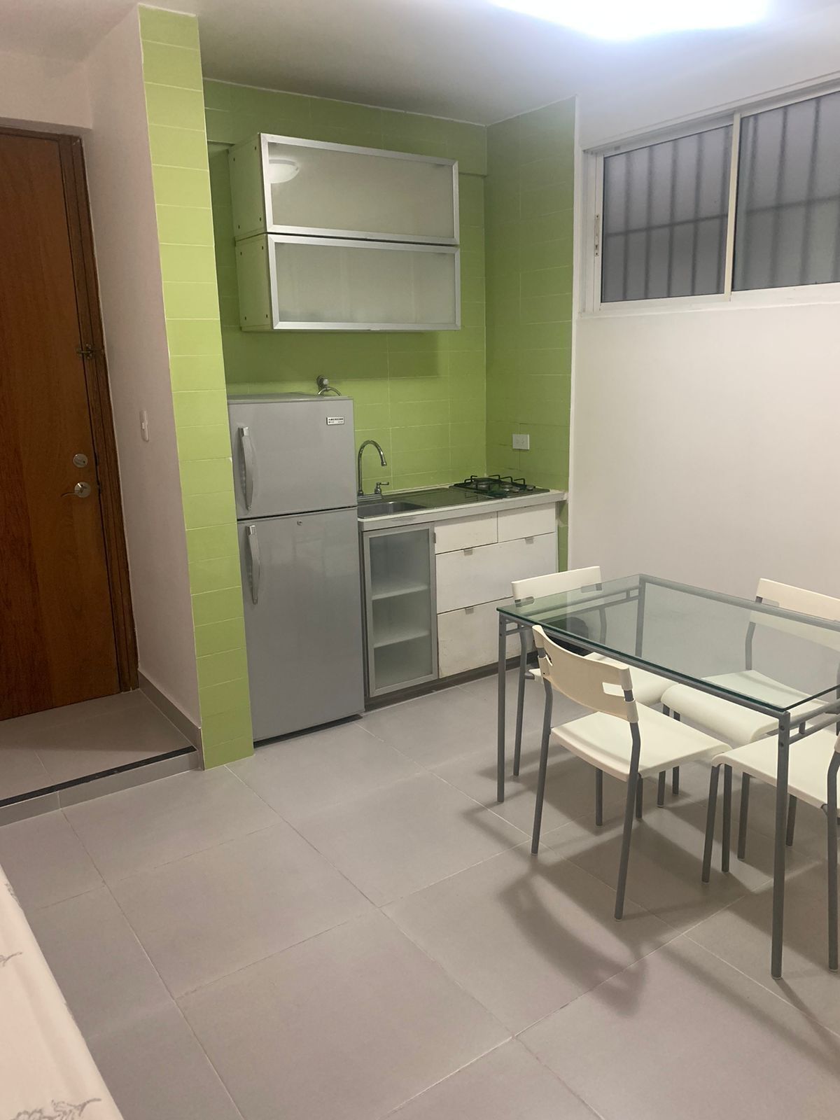 A compact kitchen with a refrigerator, stove, and white cabinets.