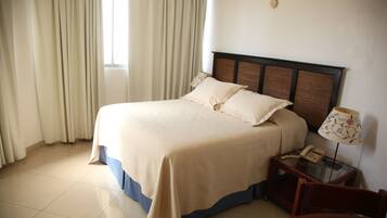 A hotel room with a bed, a bedside table with a lamp, and a chair.