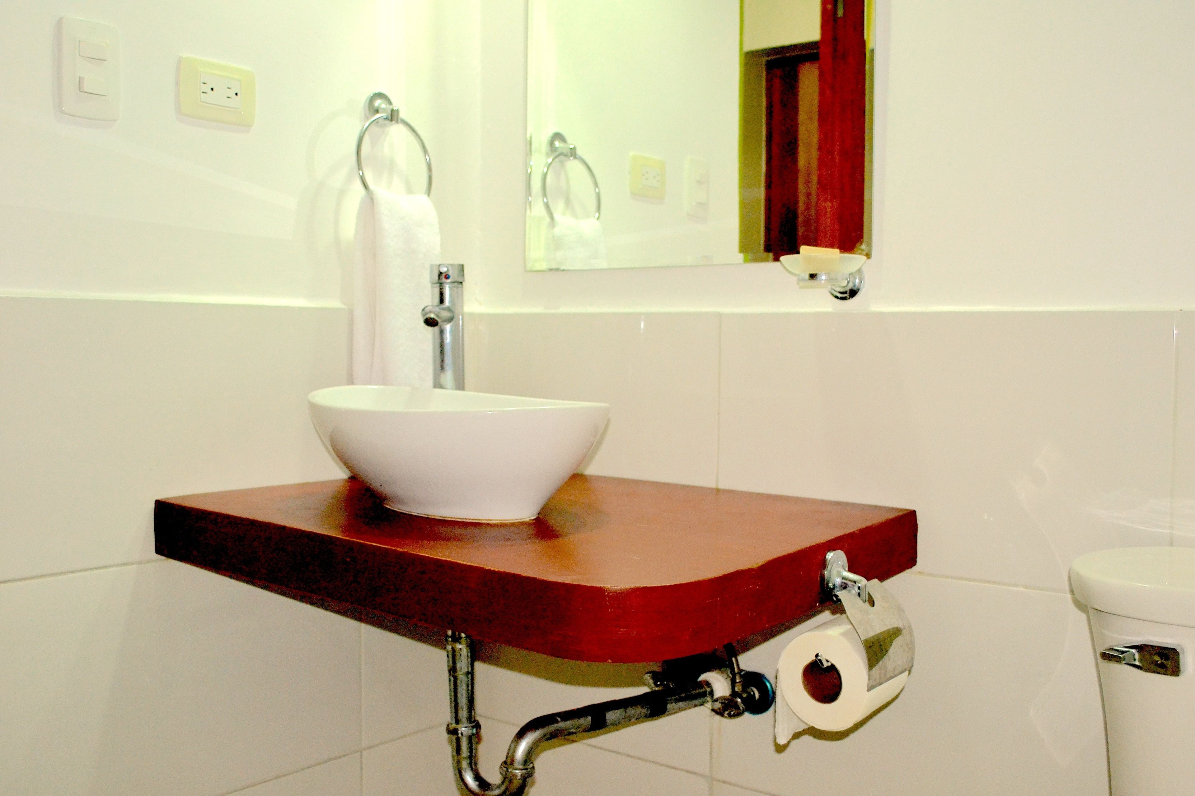 Une salle de bain avec un lavabo blanc, un miroir et des toilettes.
