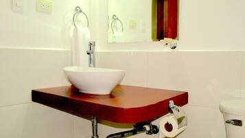 Une salle de bain avec un lavabo blanc, un miroir et des toilettes.