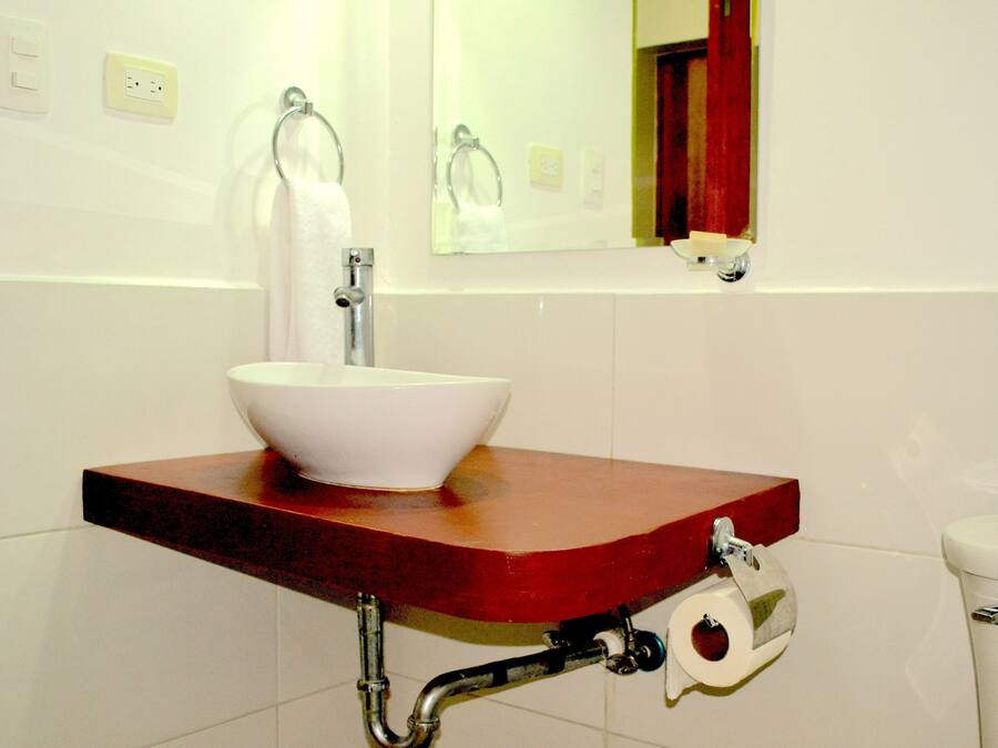 Une salle de bain avec un lavabo blanc, un miroir et des toilettes.