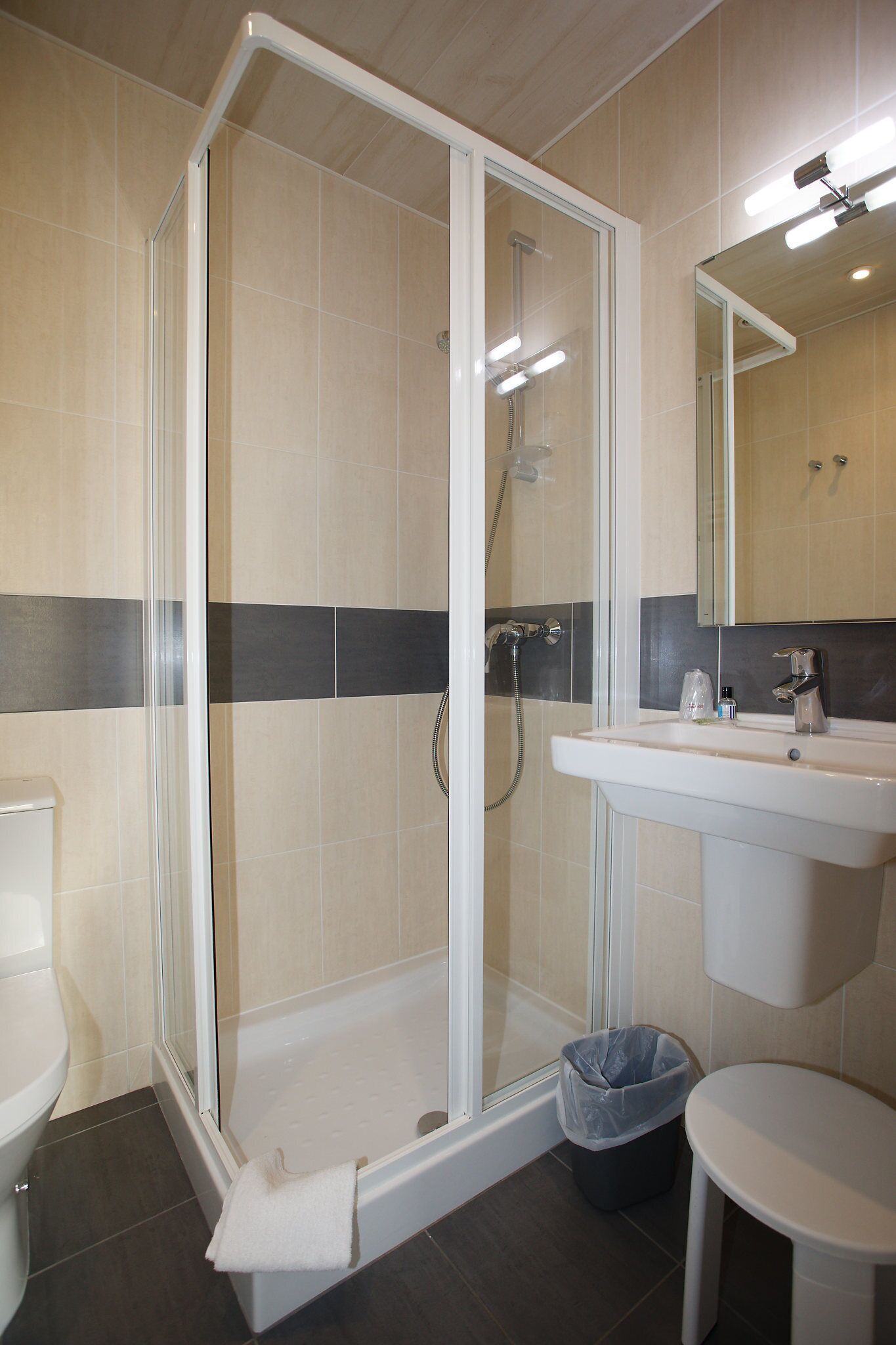 A modern bathroom with a glass-enclosed shower, a white sink, and a mirror above it.