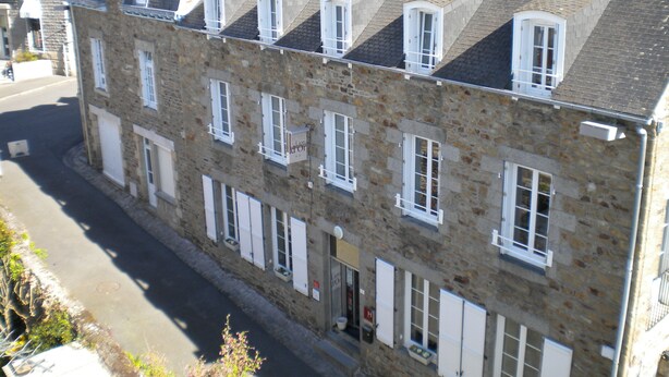 Un edificio de piedra con varias ventanas y un letrero que indica que es un hotel.