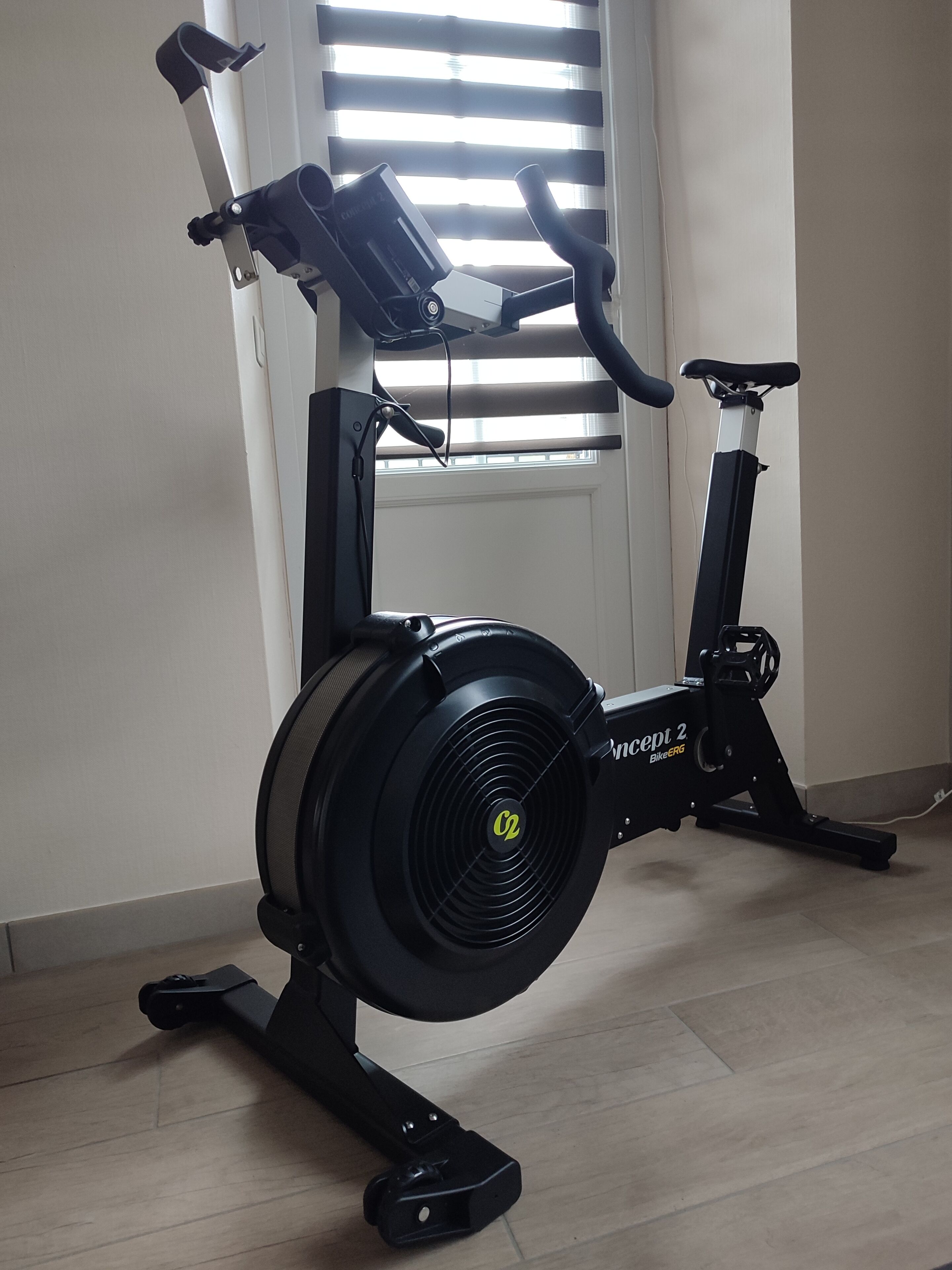 A stationary bike in a room with a window and a door.