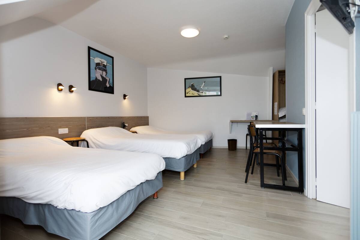 Een hotelkamer met twee bedden, een bureau en een stoel.