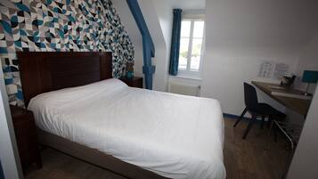 Un dormitorio con cama, escritorio y silla.