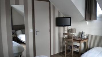 A hotel room with a bed, a desk with a chair, a television, and a window with curtains.