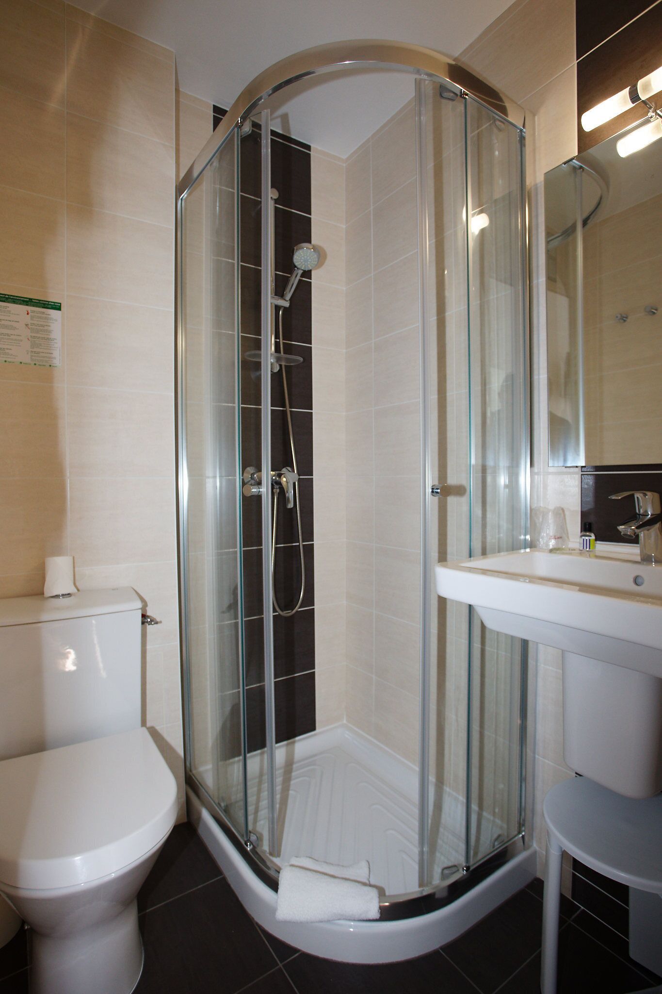 Een moderne badkamer met een douchecabine van glas, een wit toilet en een wastafel met spiegel.