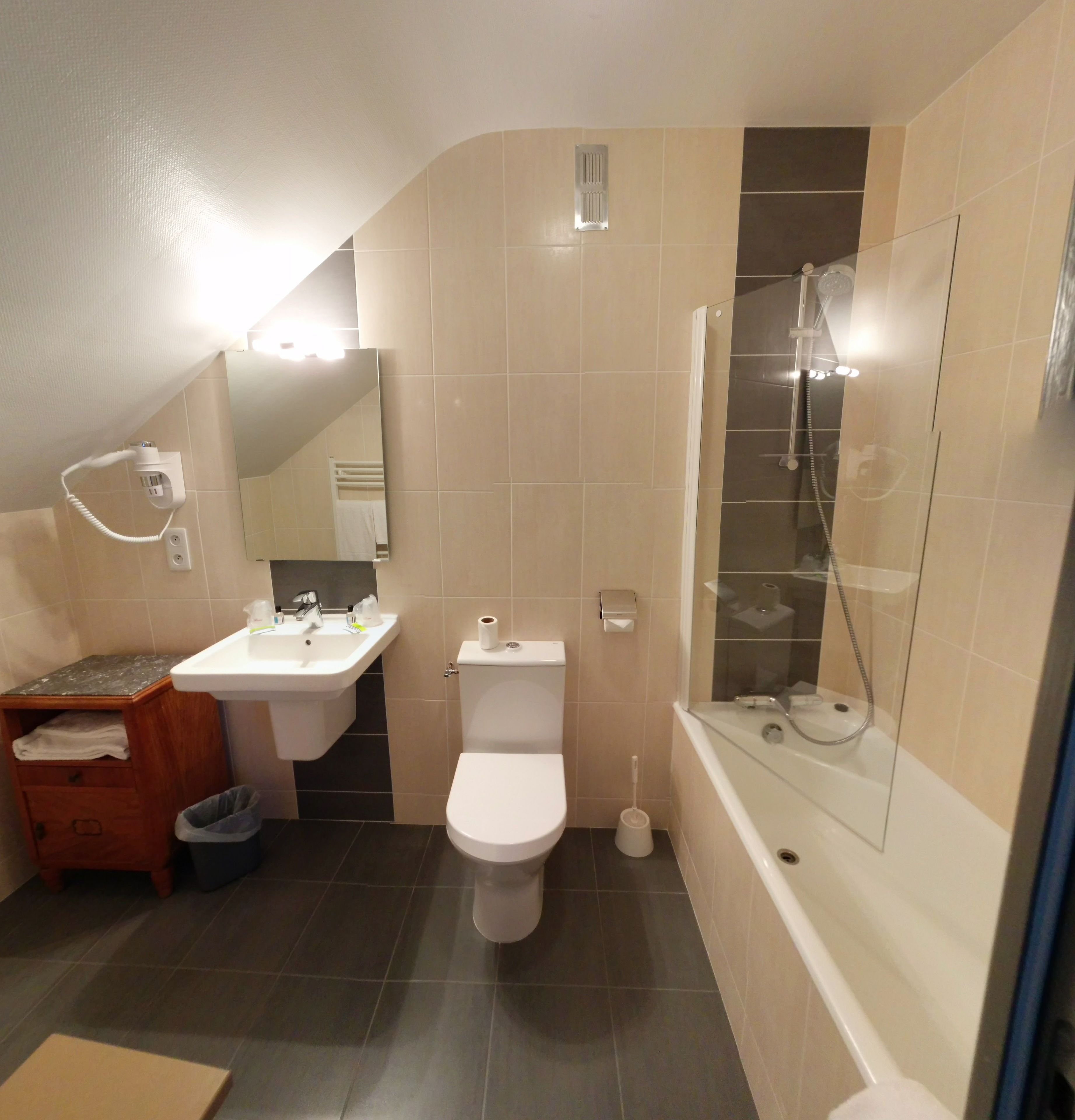 Een moderne badkamer met een wastafel, toilet en douchecabine met glazen wanden.