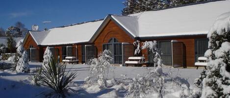 A snow-covered lodge with a wooden exterior and a covered patio area.
