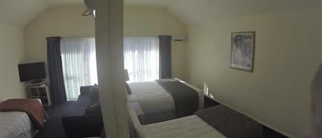 A hotel room with a bed, a desk, a chair, and a television.