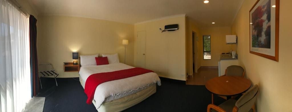 A hotel room with a bed, a desk, a chair, and a small table.