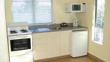 A compact kitchen with a stove, oven, microwave, sink, and dishwasher.