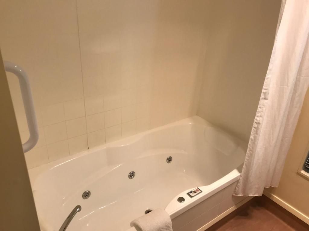 A bathroom with a white bathtub, a shower curtain, and a towel rack.