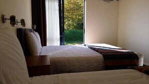 Un dormitorio con una cama grande, una mesita de noche y una ventana que ofrece vistas al verdor.