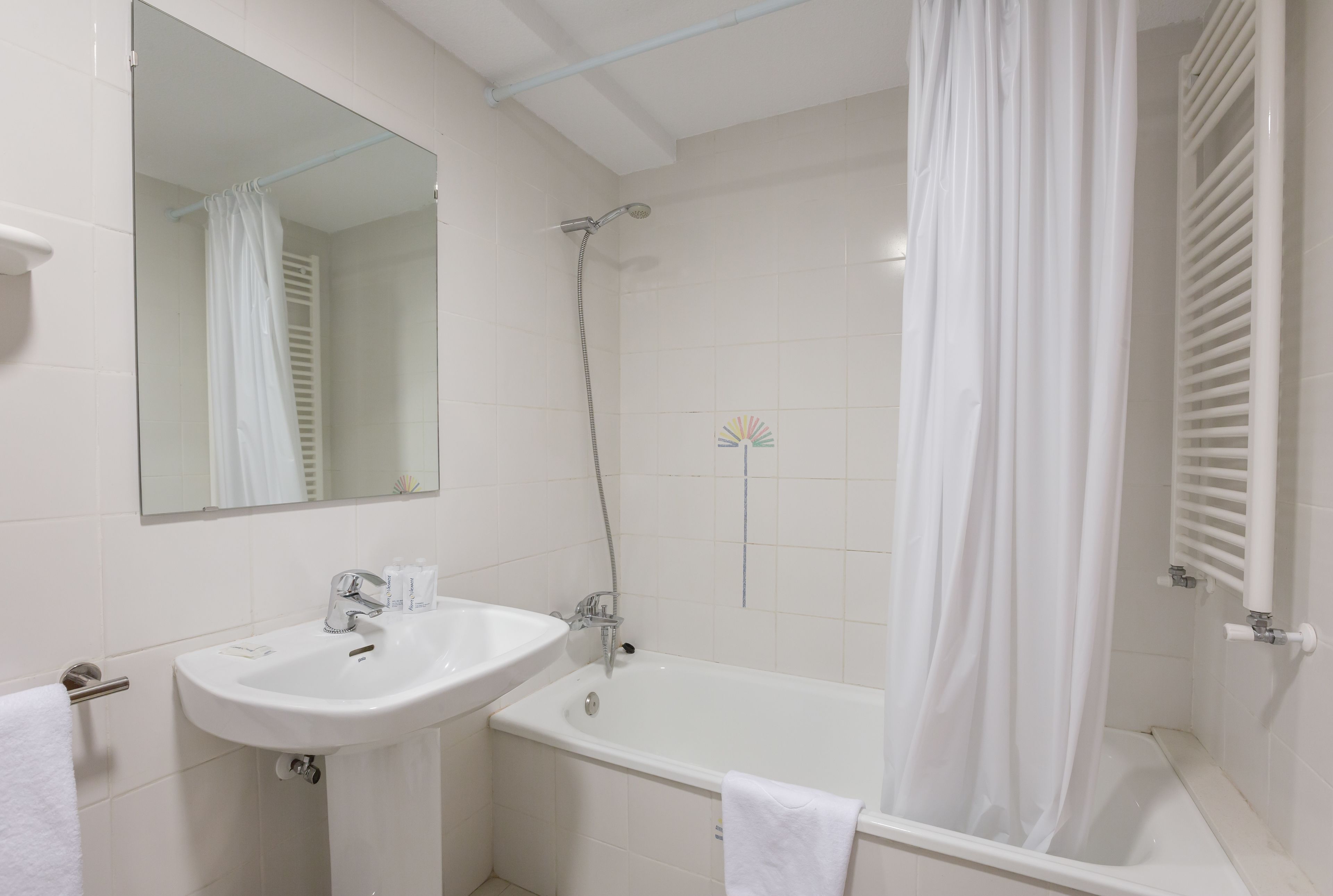 Een badkamer met een wit wastafel, een bad en een douchegordijn.