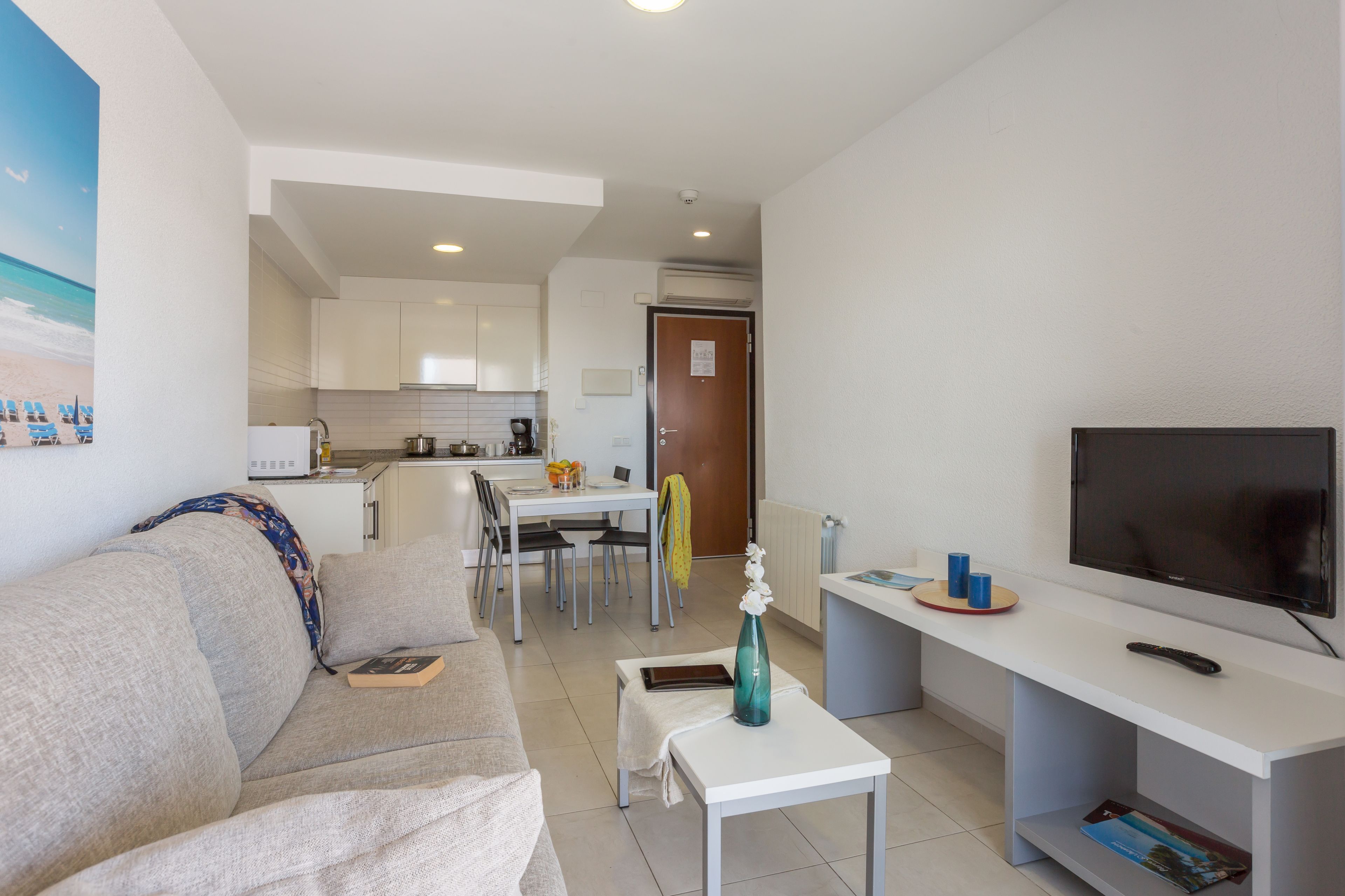 A modern living room with a sofa, a coffee table, a TV, and a dining area with a table and chairs.