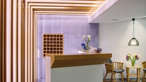 Een moderne receptie met een houten receptiebalie, een zithoek met stoelen en een wandmontage display.