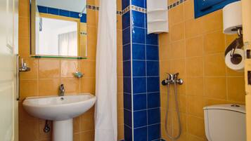 A bathroom with a white sink, a shower, and a toilet.
