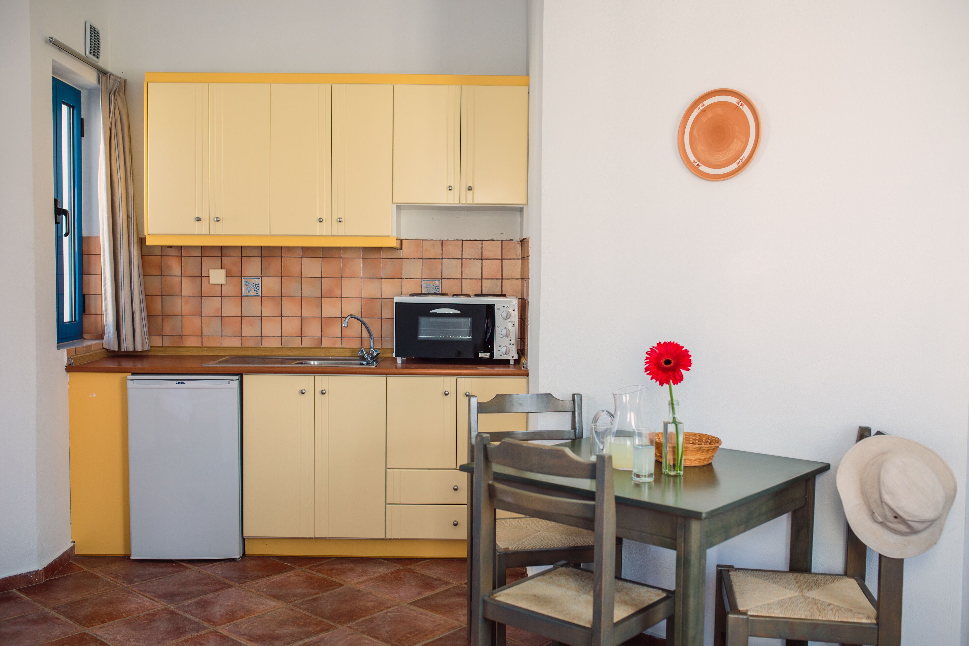 A compact kitchen with yellow cabinets, a microwave, and a small refrigerator.