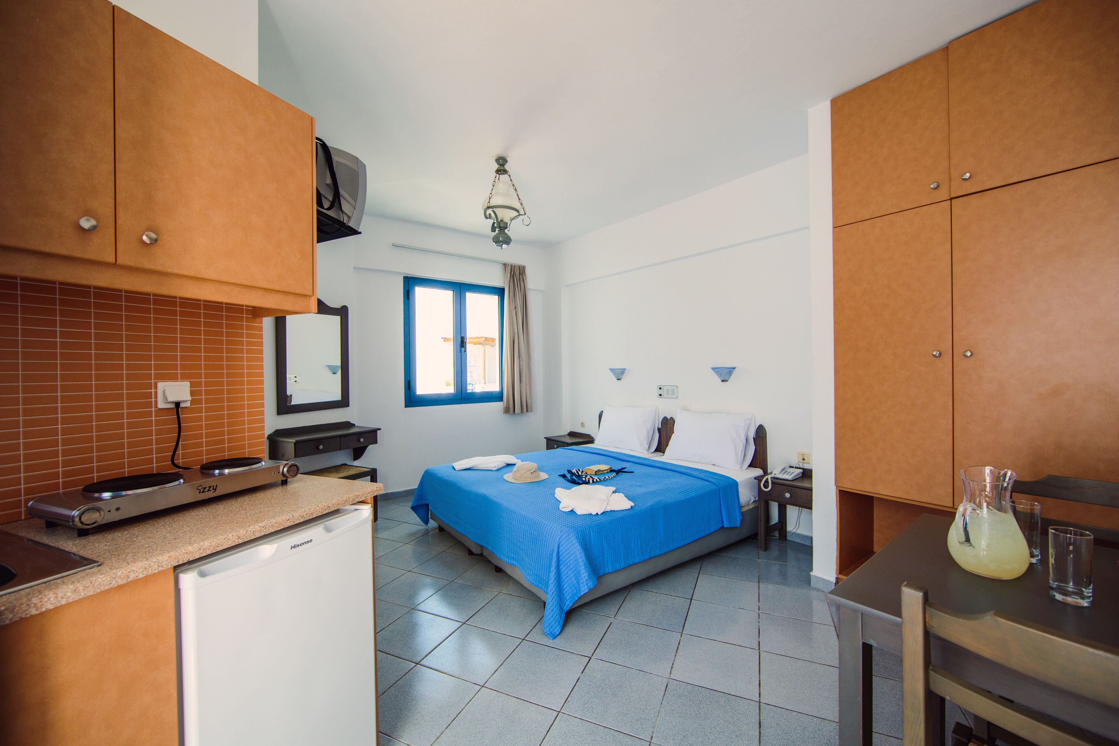 Ein kleines Hotelzimmer mit Bett, Nachttisch und einer kleinen Küchenzeile.