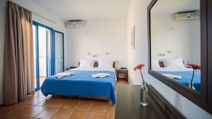 Een hotelkamer met een groot bed, een nachtkastje, een spiegel en een raam met gordijnen.