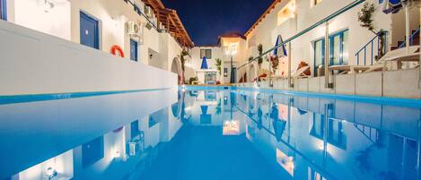 Una piscina al aire libre de temporada, sombrillas, tumbonas