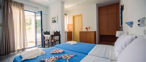 Habitación de hotel con cama, escritorio, silla, armario y baño visible a través de una puerta abierta.