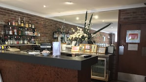 A bar area with a brick wall, shelves of liquor bottles, a counter with a bowl of snacks, and a 'STAFF ONLY' sign.