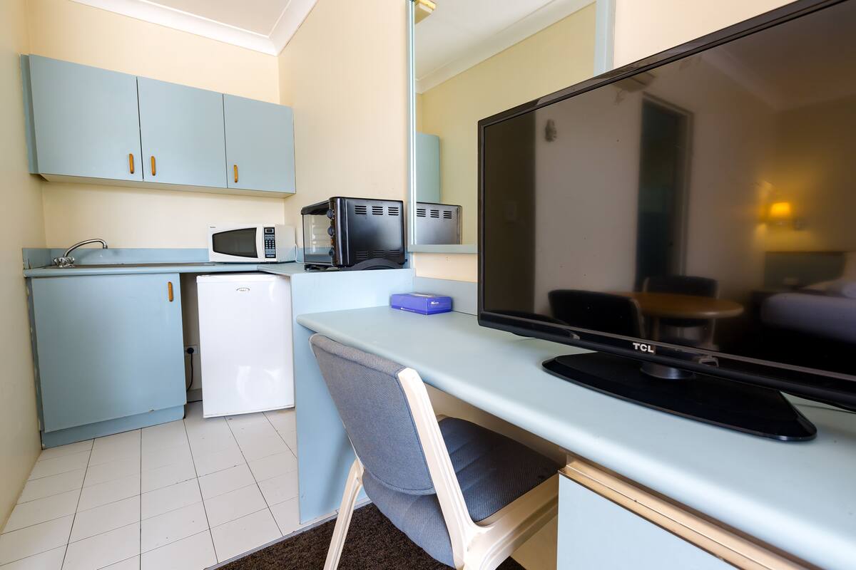 Uma cozinha compacta equipada com micro-ondas, torradeira e pequeno frigorífico.