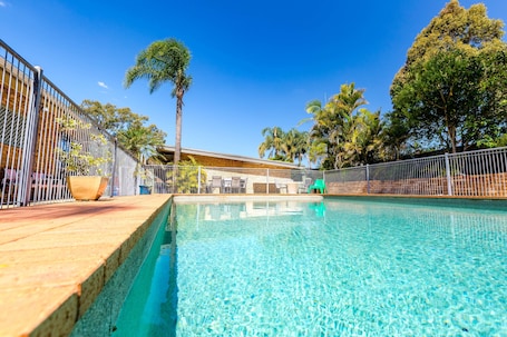 Una piscina al aire libre, sillones reclinables de piscina