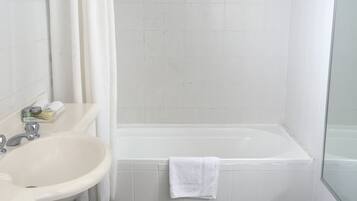 Un baño con bañera, lavamanos y cortina de ducha.