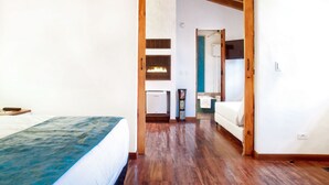 A bedroom with a bed, a wooden ceiling, and a hallway leading to a bathroom. - Hotel Casona de Usaquén (Bogotá)