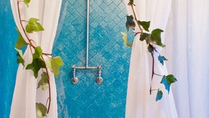 A bathroom with a bathtub, blue tiled walls, and white curtains. - Hotel Casona de Usaquén (Bogotá)