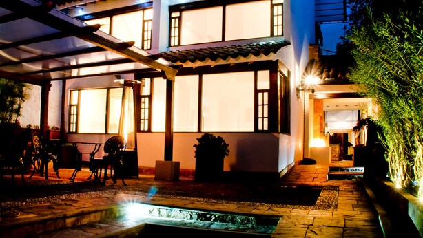 A two-story house with a covered patio, outdoor seating, and a small water feature. - Hotel Casona de Usaquén (Bogotá)