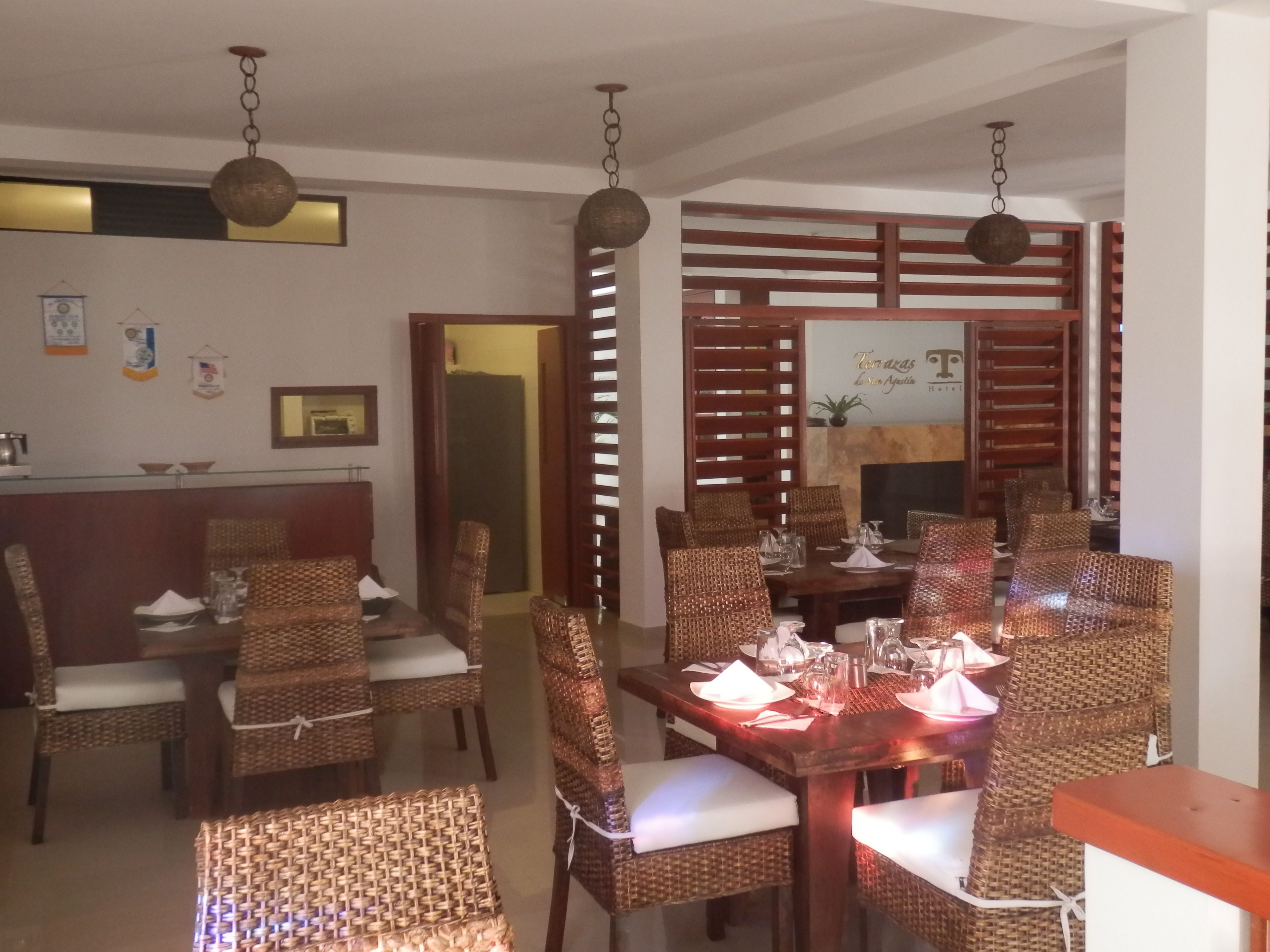 A dining area with wicker chairs and a wooden table set for a meal.