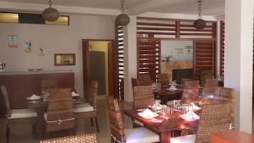 A dining area with wicker chairs and a wooden table set for a meal.
