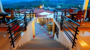 Una escalera conduce a una terraza con mobiliario exterior y vistas a un pueblo.