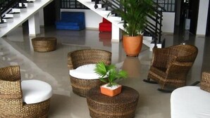 Un vestíbulo moderno con mobiliario de mimbre, una escalera y una planta en maceta.