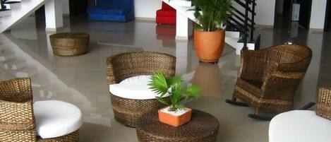 A modern lobby with wicker furniture, a staircase, and a potted plant.