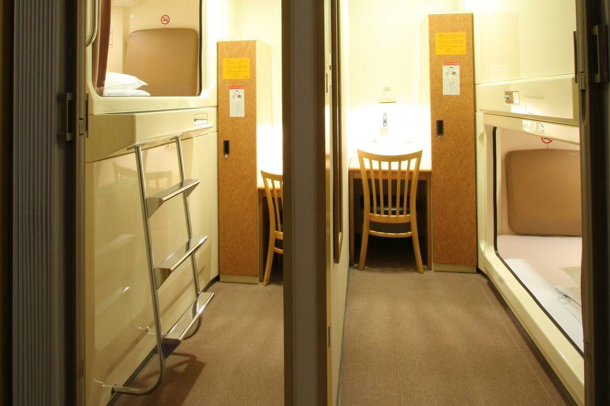 A compact room with a bunk bed, a small table with chairs, a mirror, and a cabinet.