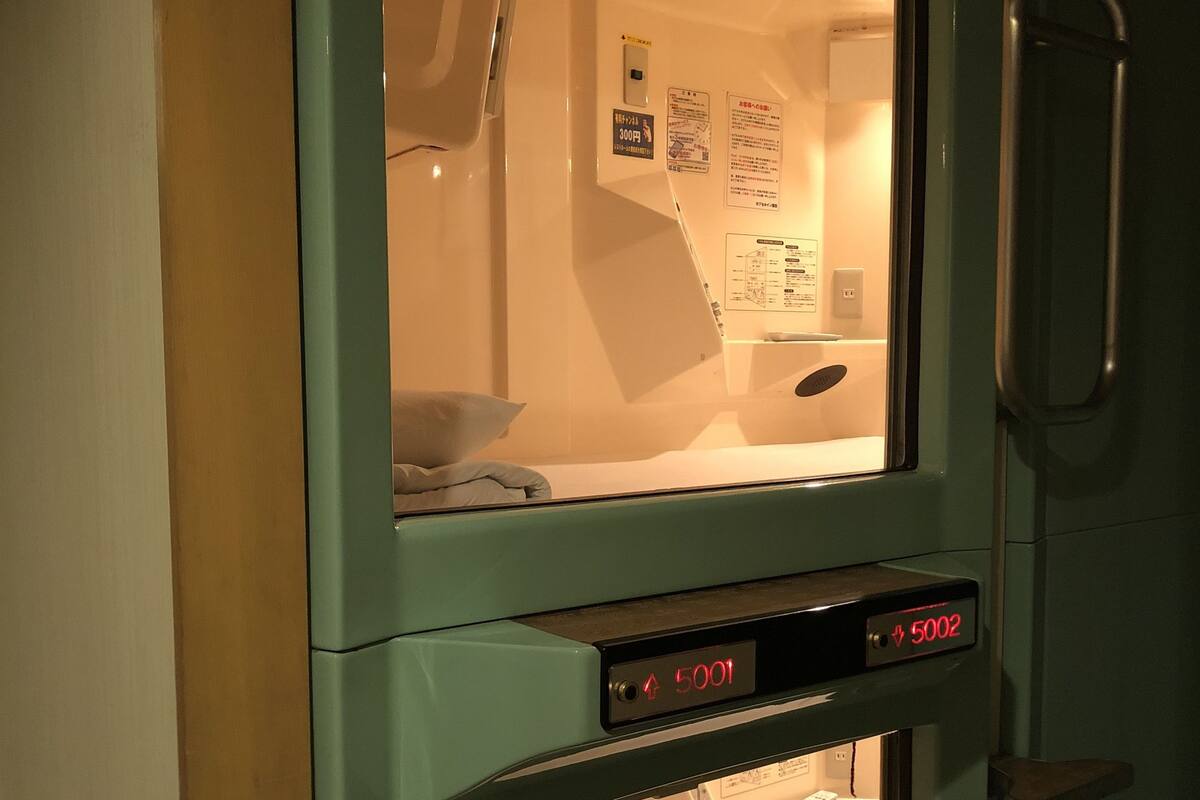 A room with a bed, a window, and a control panel with numbers.
