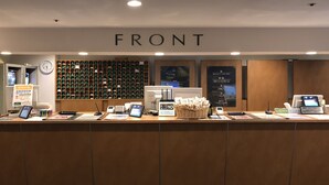 A reception desk with a clock, a wall of green gift boxes, and a sign indicating room rates. - Capsule Inn Kamata (Tokyo)