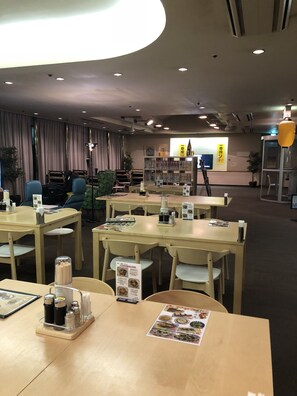 A modern hotel lobby with multiple seating areas, a reception desk, and a large bookshelf. - Capsule Inn Kamata (Tokyo)