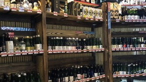 A liquor store with multiple shelves stocked with bottles, wooden display stands, and price tags. - Capsule Inn Kamata (Tokyo)