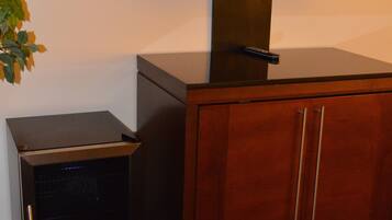 Un televisor montado en un mueble con un escritorio pequeño y una planta a su lado.
